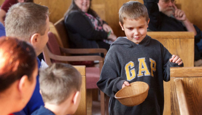 Boy passes the collection basket during Sunday service.
