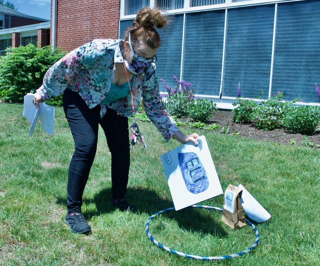 Jenny Delgizzi places Coming of Age participant Elisabeth’s scrapbook within a hula hoop on the front lawn of the church on May 31, 2020. The hoops will be used for spacing for a socially-distanced group photo.