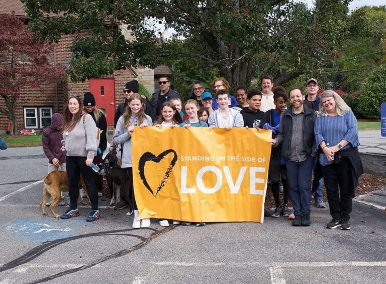 CROP walk is Oct 19. The CROP walk team standing behind a "standing on the side of love" banner - CROP walk is to support our Loaves and Fishes Food panty -