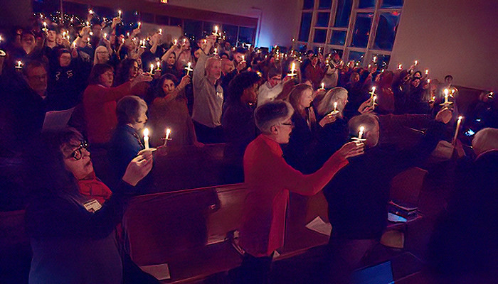 UUCW Holiday Candlelight Service December 2026 People holding candles up during UU Church of Worcester Holiday Candlelight Service 2026